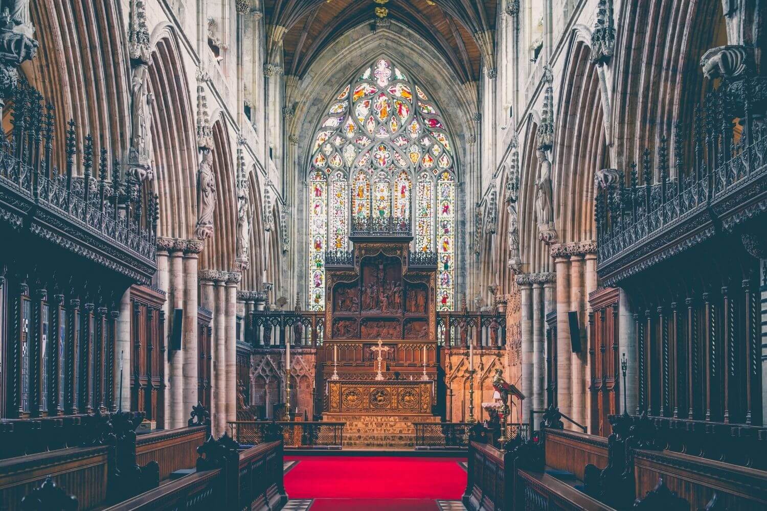 Interior of an ornate, Gothic-style church building, featuring the Altar and choir pews